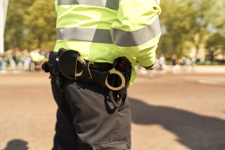 Police officer standing in a public area, providing security and maintaining order while wearing a high visibility jacket and uniform