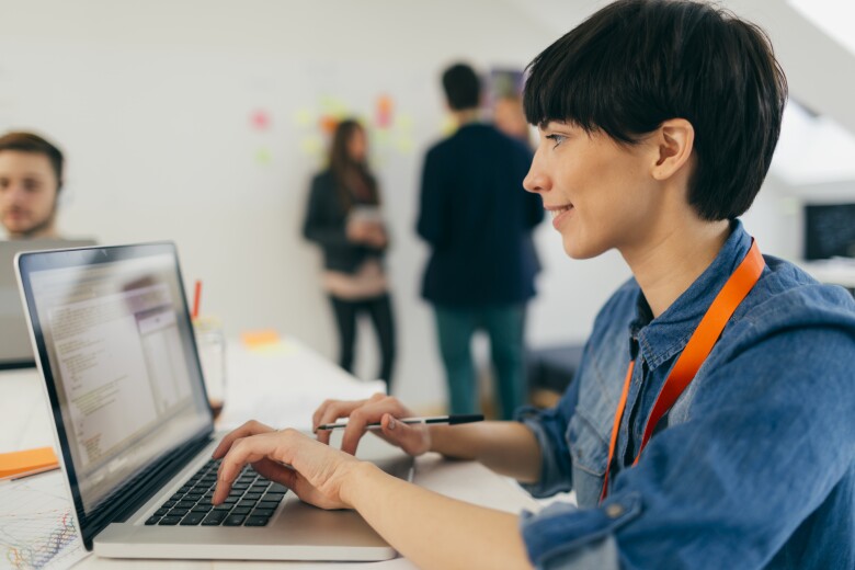 young developer reviewing work on her laptop in the office