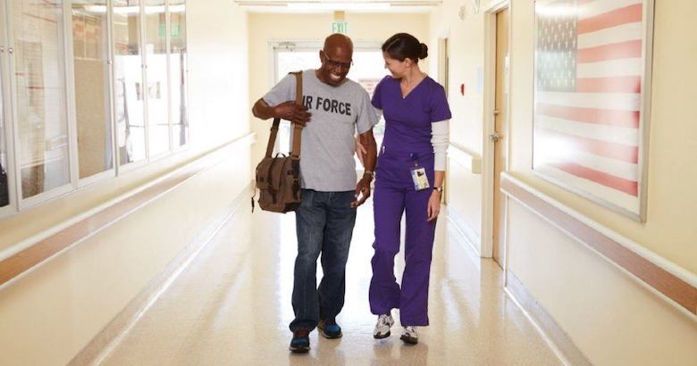 nurse walking with veteran patient in hospital hallway