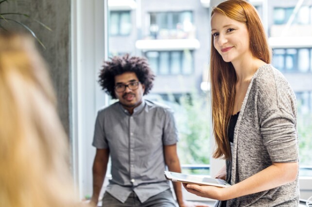 two coworkers looking at a third while having a conversation in the office