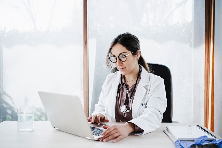 Doctor in her office looking at patient records on her laptop